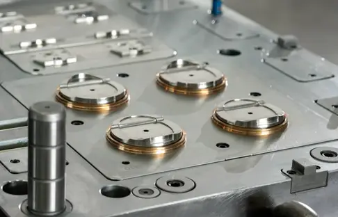 Close-up of a precision steel injection mold with circular inserts and a guide pin for automotive plastic components