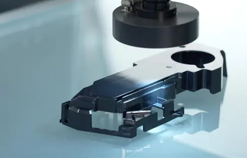 Black injection-molded plastic part under automated optical inspection with focused lab lighting