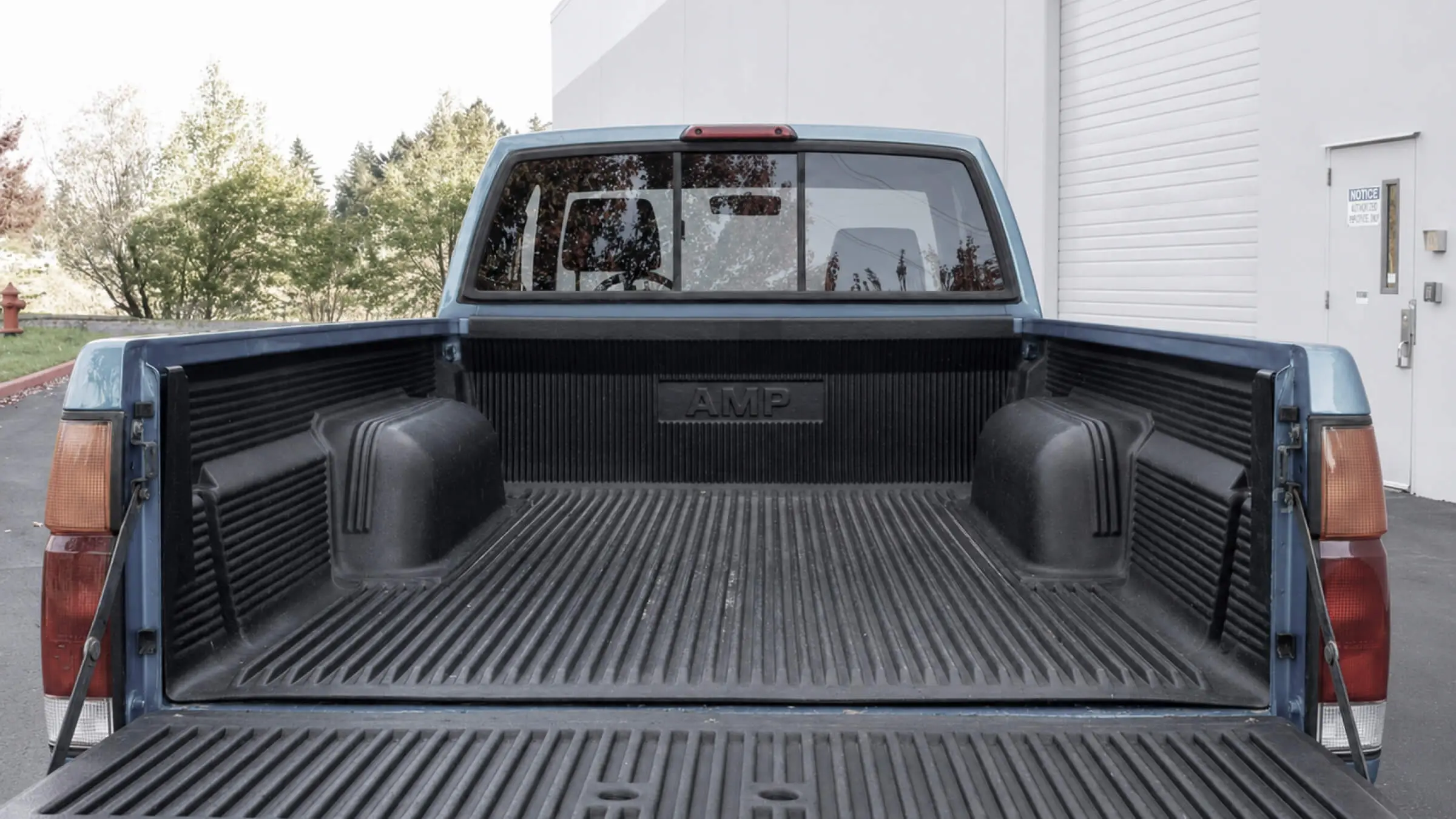 AMP logo embossed on an injection-molded automotive truck bed liner installed in a pickup truck