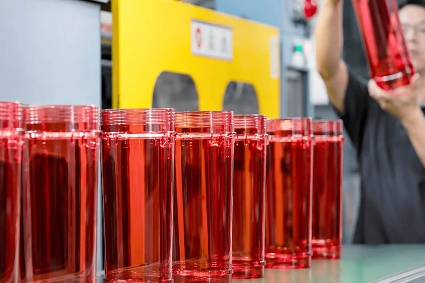 AMP inspector checking transparent red Eco Elephant fire extinguisher bodies on the production line for powder level and shell clarity