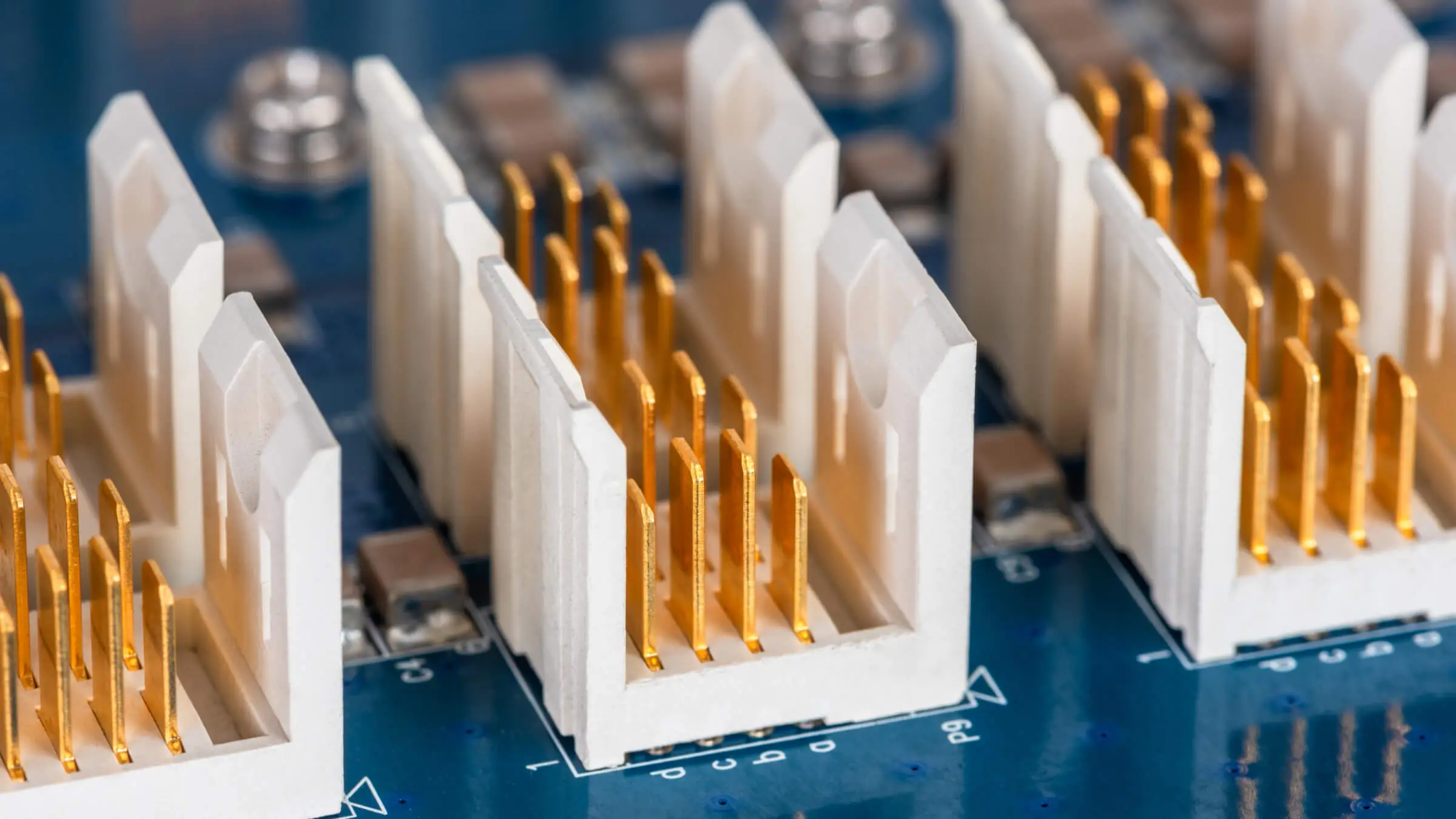 Close-up of gold-plated connector pins in white plastic housings on a circuit board, manufactured by AMP