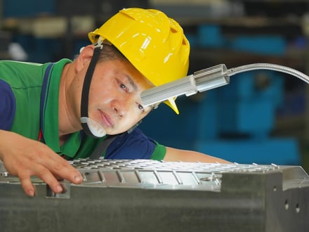 AMP toolmaker inspecting your export mold cavity surface finish and fit under task lighting as part of our sign-off process before the mold ships to your facility