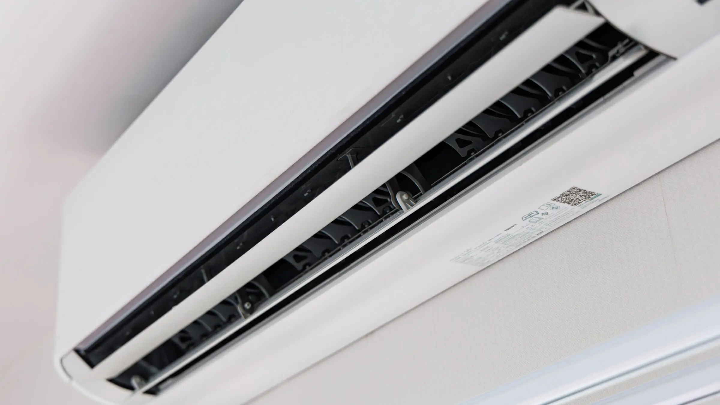 Close-up of an injection-molded white air conditioner indoor unit housing with vent details, manufactured by AMP