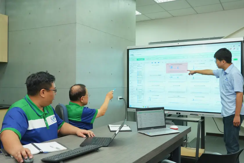 AMP engineers reviewing live injection molding process data on a production-floor monitor