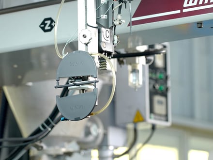 AMP robotic end-of-arm tooling gripping a freshly molded component using vacuum suction for automated extraction from the injection molding press