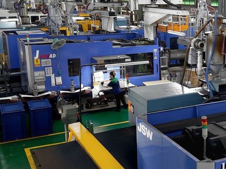 AMP operators performing inspection, trimming, and packaging of injection-molded components at press-side workstations for direct shipment