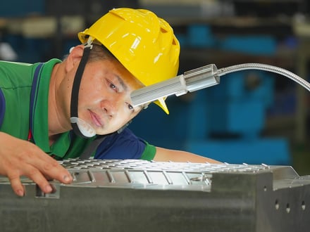 AMP toolmaker closely inspecting mold cavity surface finish and fit under task lighting before the tool is approved for trial