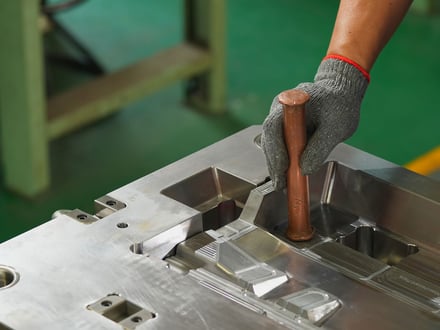AMP toolmaker using a copper drift to seat cavity inserts into the mold base during assembly, ensuring precise fit without damaging hardened steel surfaces