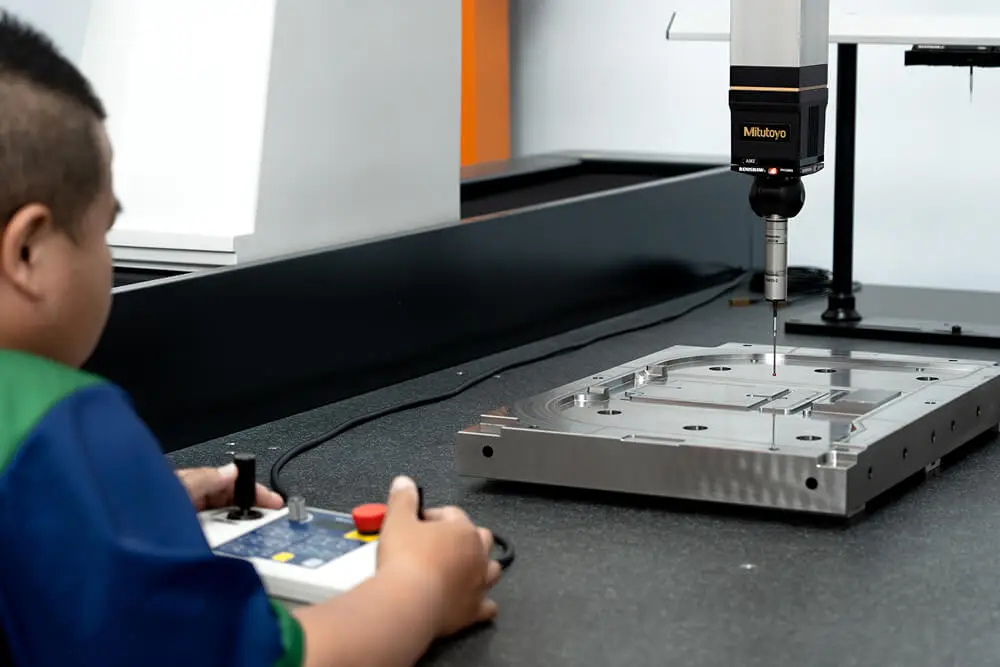 AMP operator measuring a machined mold component on our Mitutoyo S9168 CMM with Renishaw probe, confirming critical dimensions against CAD data before mold assembly