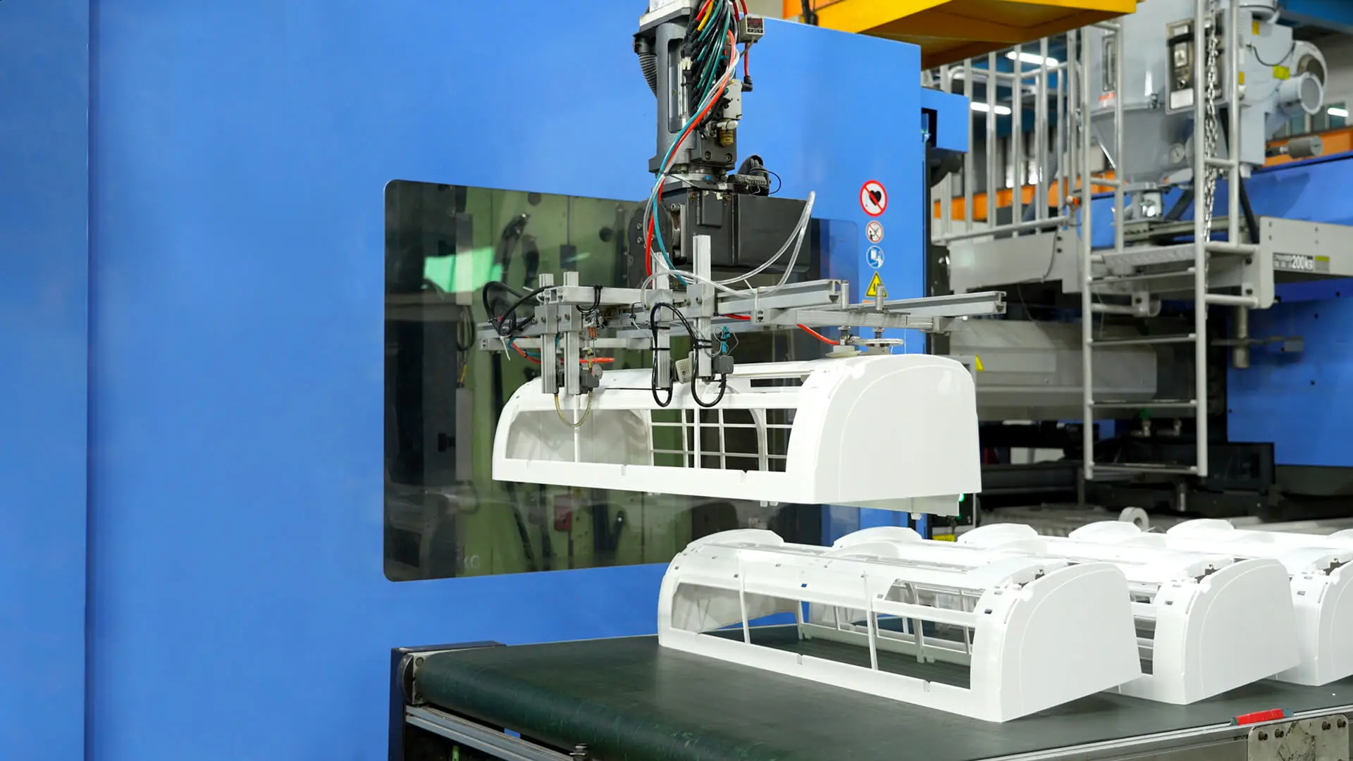 AMP robotic arm extracting a large white plastic housing from an injection molding press as part of our one-stop molding service