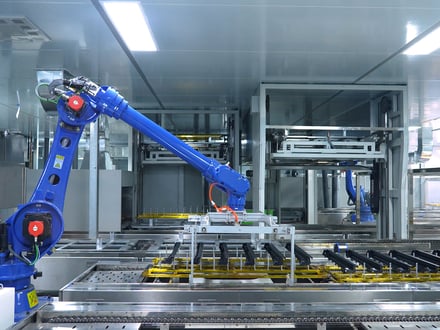 AMP's six-axis robot loading parts onto the conveyor inside our automated spray painting clean room for consistent, high-volume surface finishing in-house