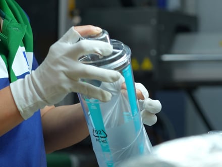 AMP operator inspecting a transfer-printed product for decoration quality before packaging, all handled in-house