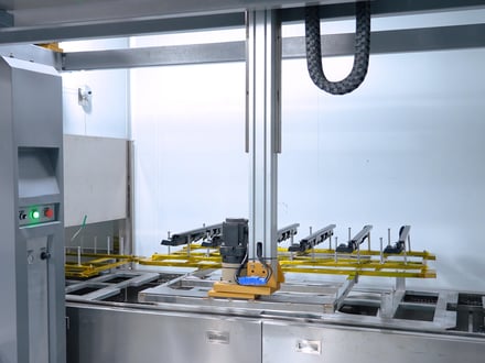 AMP's robotic spray gun and part fixtures inside our enclosed clean room paint booth, applying controlled surface coatings to injection-molded components in-house