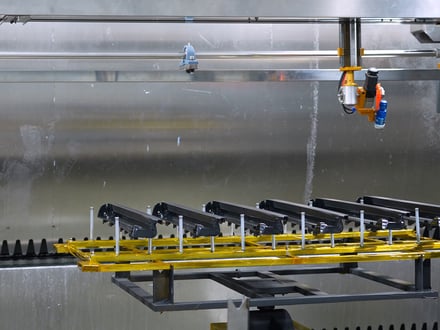 AMP's automated spray nozzle applying surface coating to fixtured injection-molded parts inside our enclosed clean room paint line