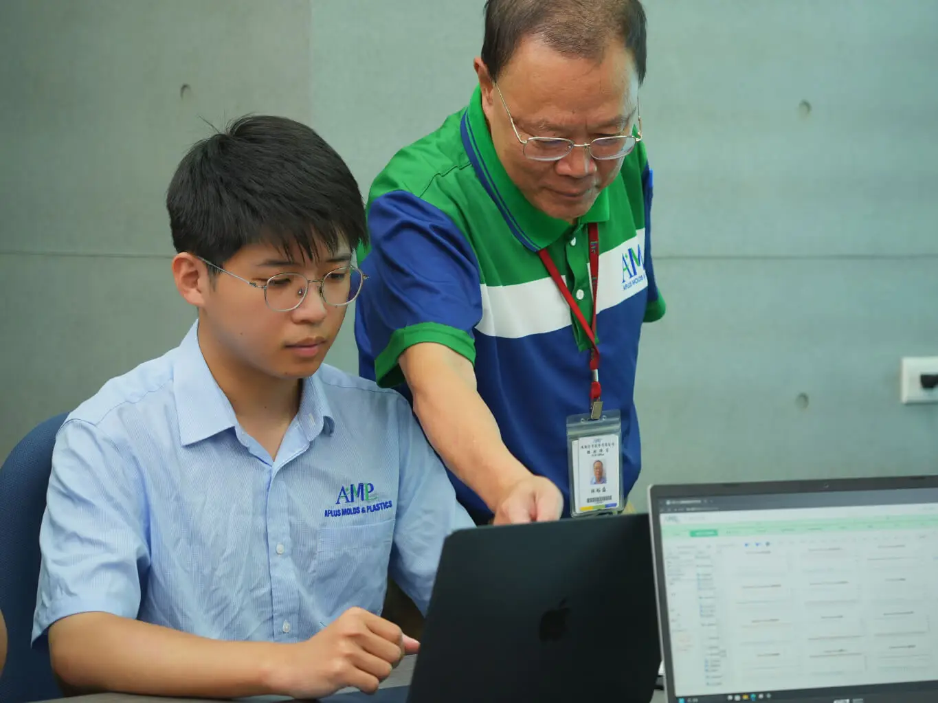 AMP engineers reviewing live process data on a laptop beside the molding floor monitoring dashboard