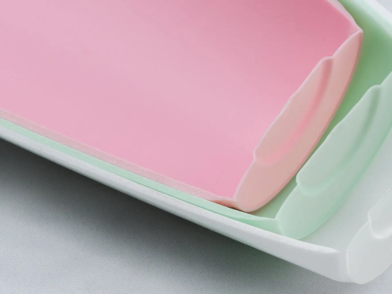 Close-up of nested pink and mint supercritical foam molded parts showing the microcellular core