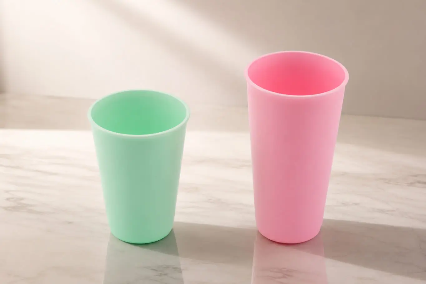 Mint green and pink supercritical foam tumblers on a marble surface, measured production parts from AMP