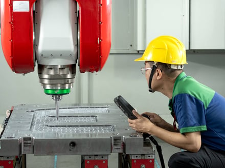 AMP operator guiding the 5-axis gantry machining center via handheld pendant while cutting detailed cavity geometry into a mold