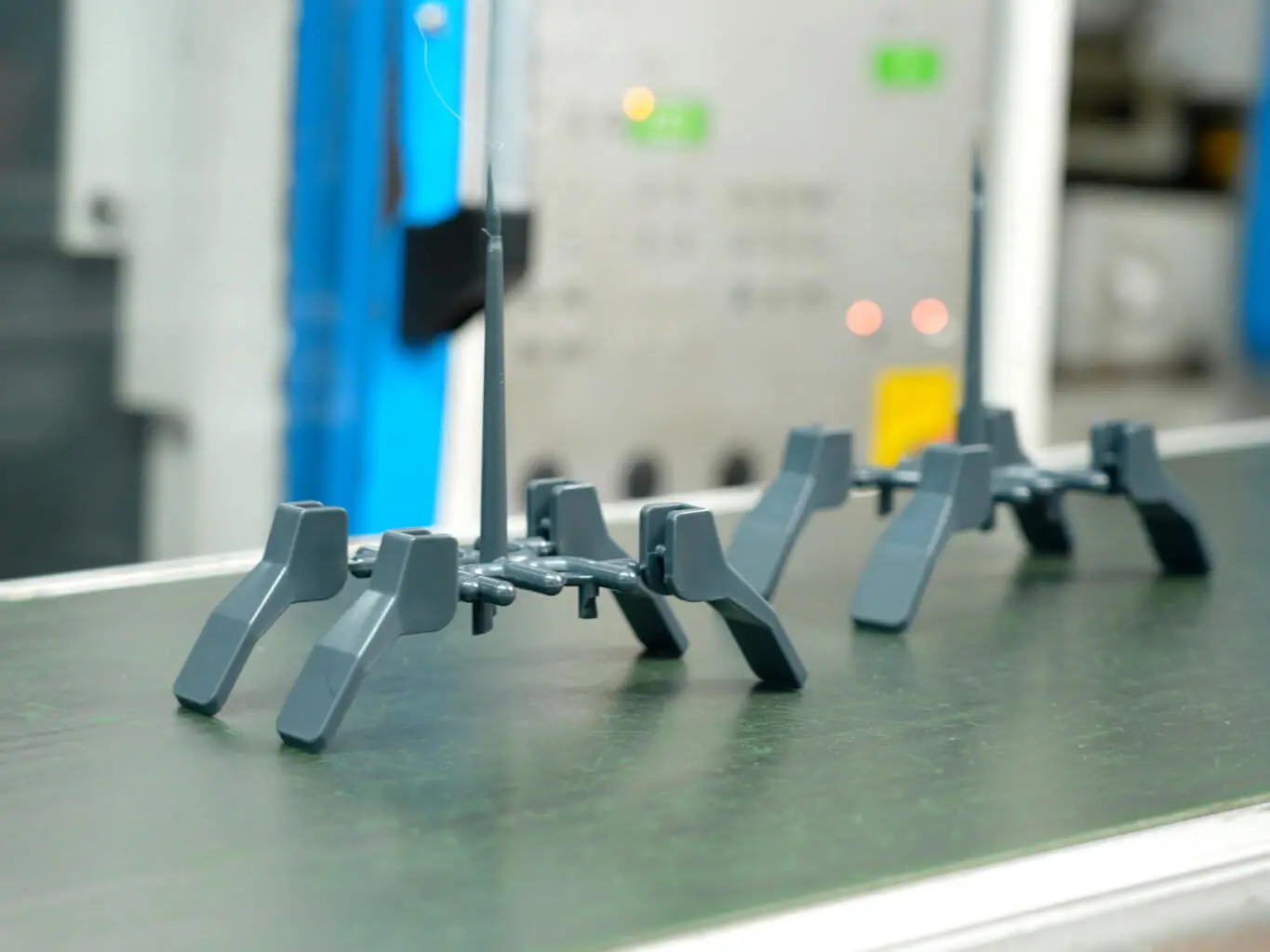 Injection-molded plastic structural components on a green conveyor belt at AMP during production